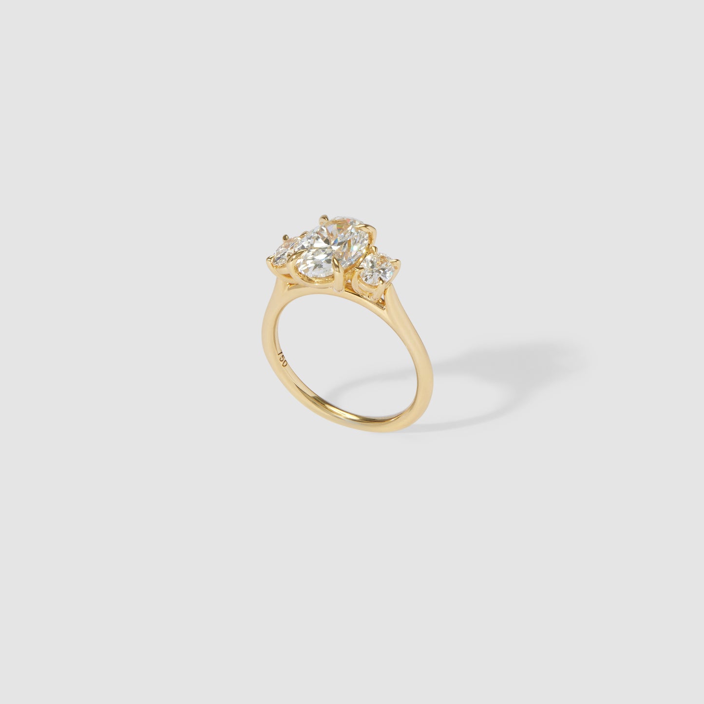 Elegant gold ring with three sparkling diamonds, set in a classic prong setting, on a plain background. Luxurious, high-end jewellery.