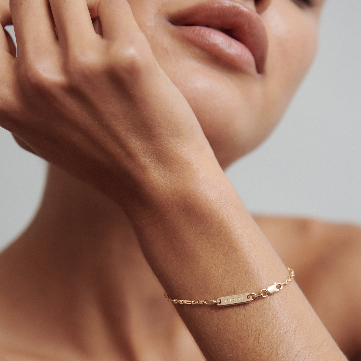 Elegant close-up of a woman's wrist showcasing a delicate gold chain bracelet with a small rectangular bar, highlighting minimalist luxury jewellery.