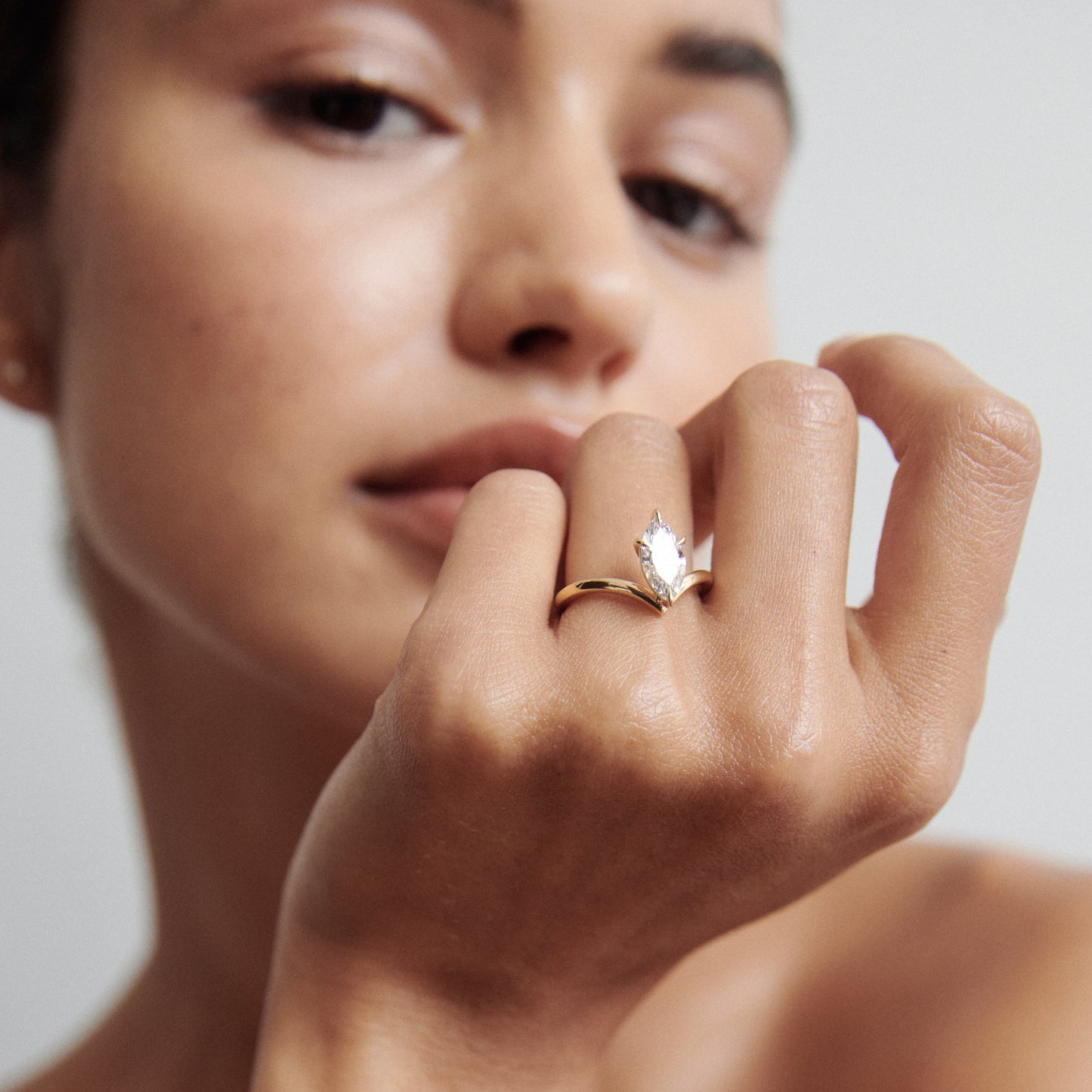 Woman elegantly displaying a gold ring with a large marquise-cut diamond. Luxury jewellery, close-up detail.