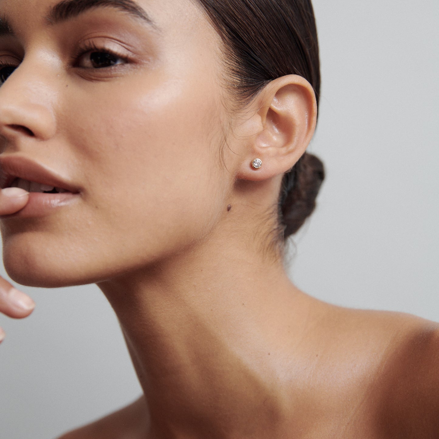 Woman showcasing a diamond stud earring, with smooth skin and sleek hair bun, representing luxury jewellery. Close-up, minimalist elegance.
[text overlay: Large Size: 4mm or 0.25ct each]