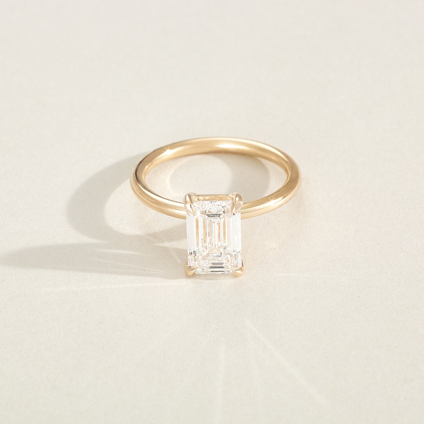 Gold ring with a diamond on a light beige background