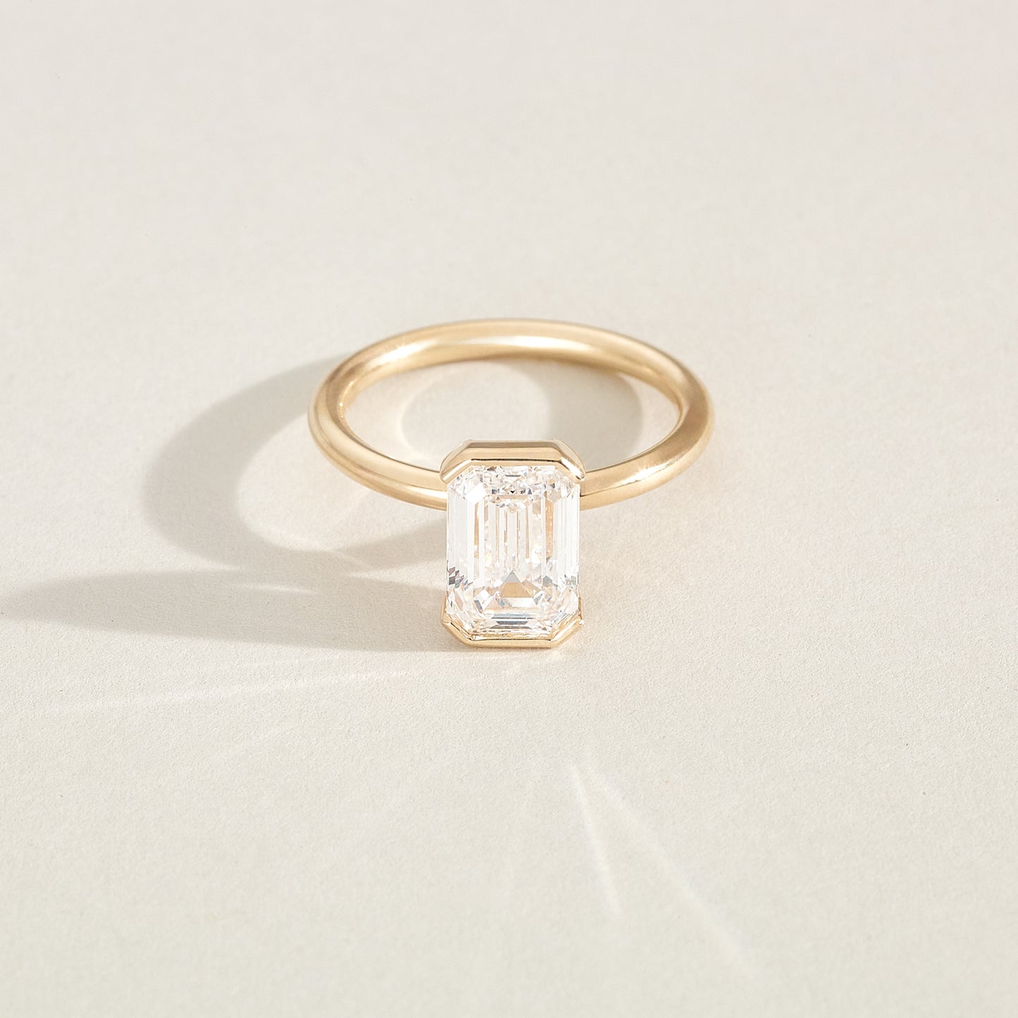 Gold ring with a rectangular diamond on a light beige background
