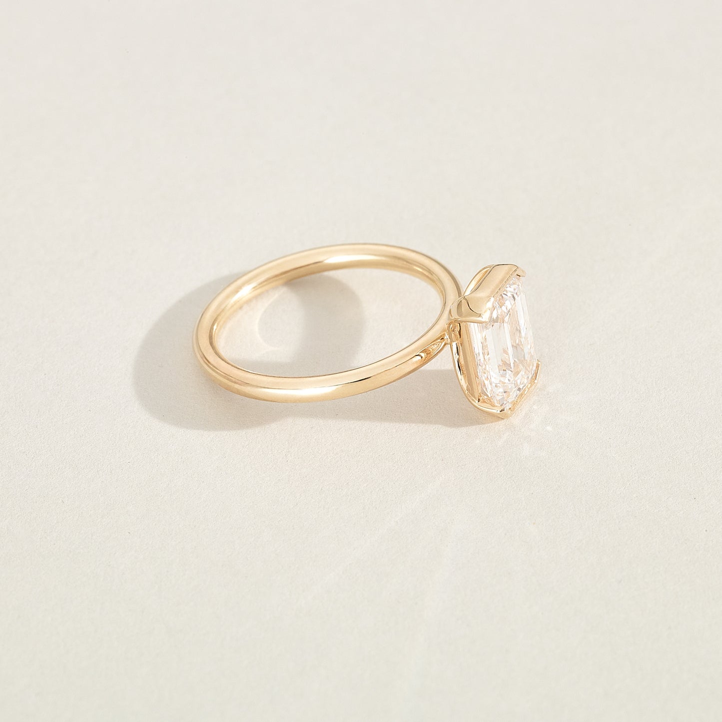 Gold ring with a diamond on a light beige background