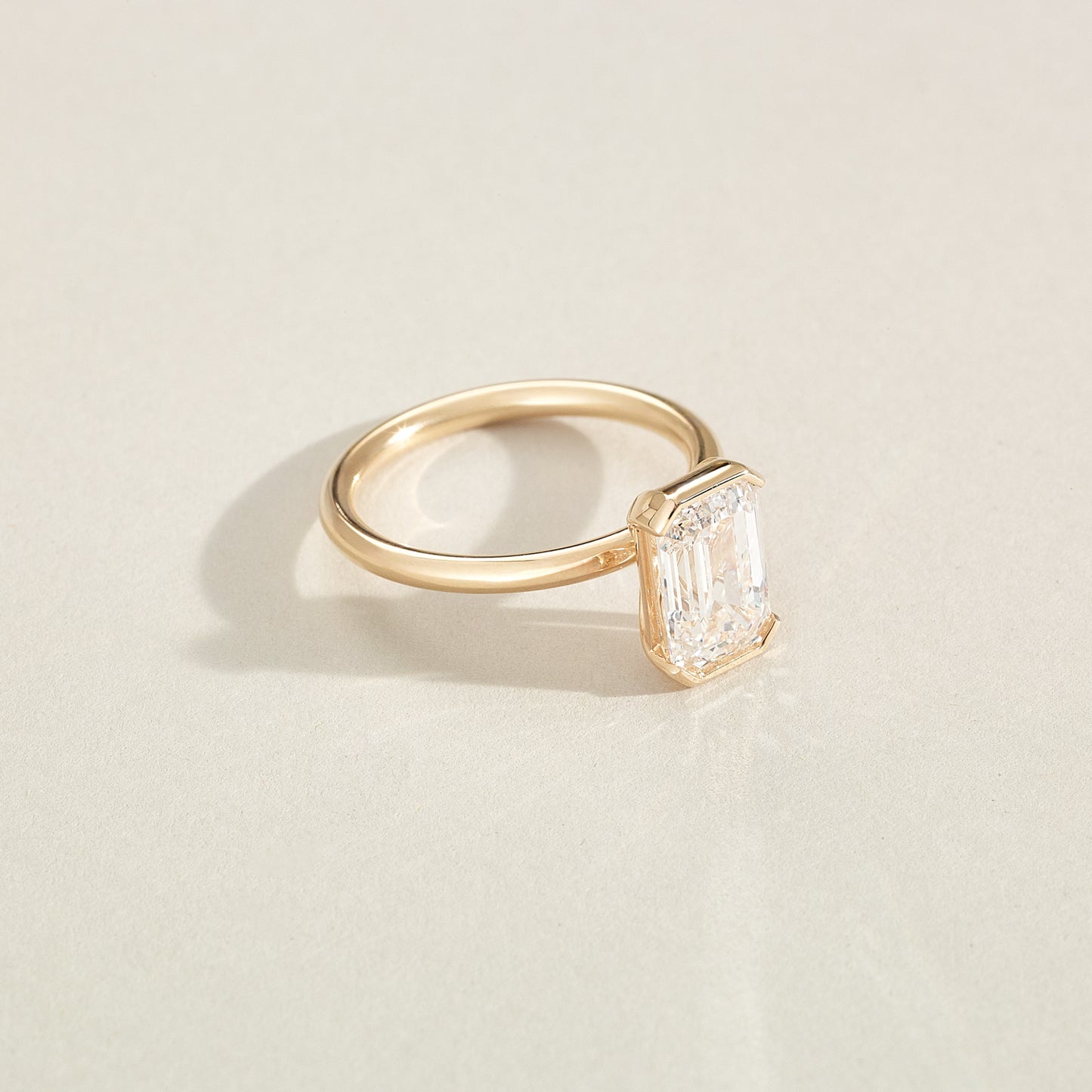 Gold ring with a diamond on a light beige background