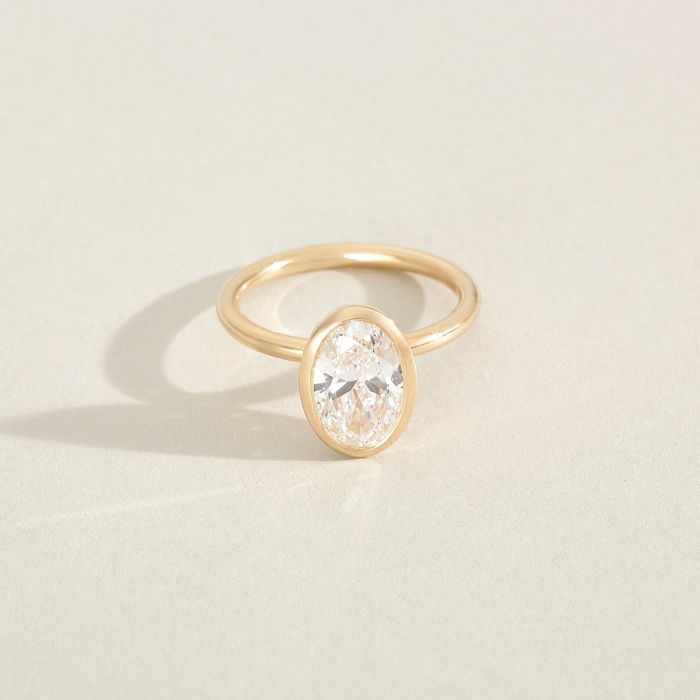 Gold ring with a diamond on a light beige background