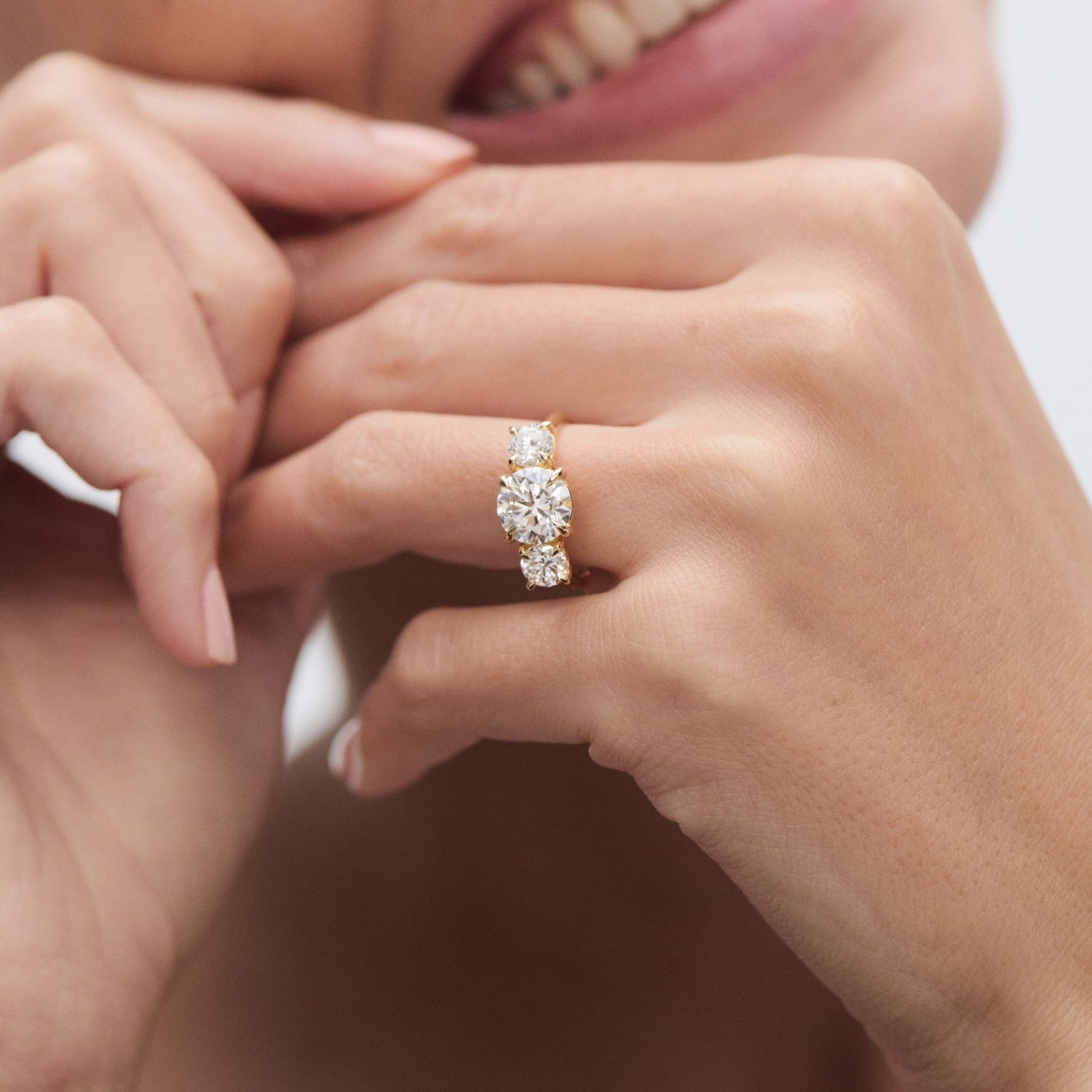 Woman's hand showcasing a gold engagement ring with three large diamonds, highlighting luxury jewellery with a sparkling, high-end appeal.