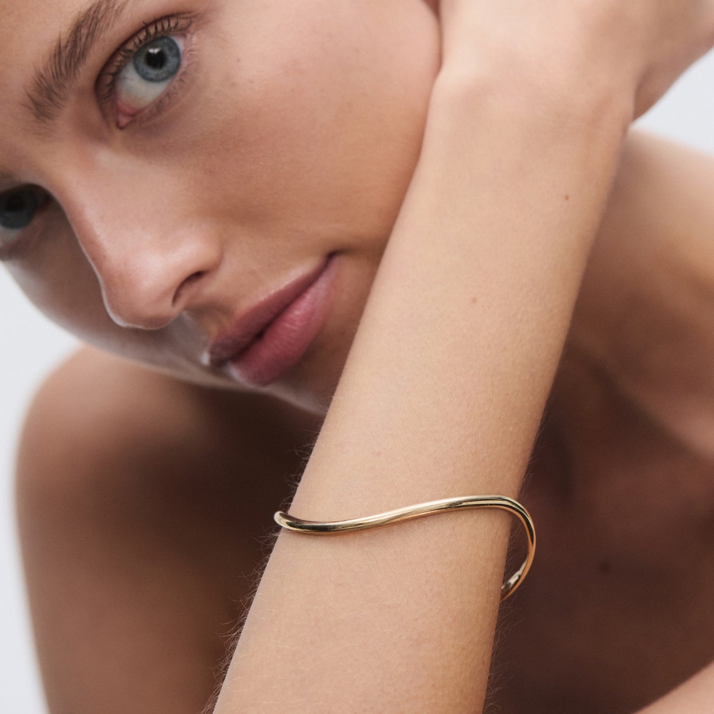 Elegant gold bracelet on a woman's arm, with a close-up showcasing minimalist design and luxury jewellery aesthetics. [text overlay: Fine] [text colour: #000000]

