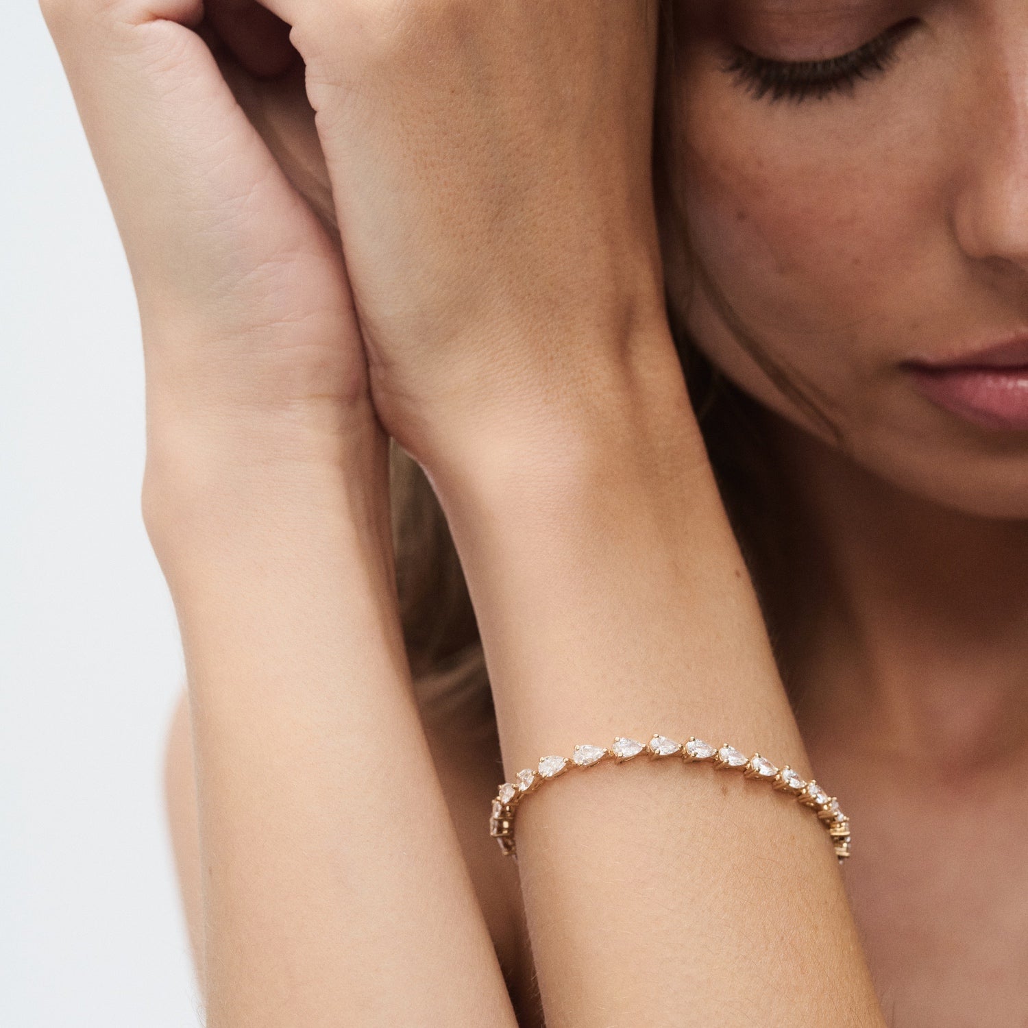 Elegant woman showcasing a diamond tennis bracelet on her wrist, set against a neutral background. Perfect for luxury jewellery styling.