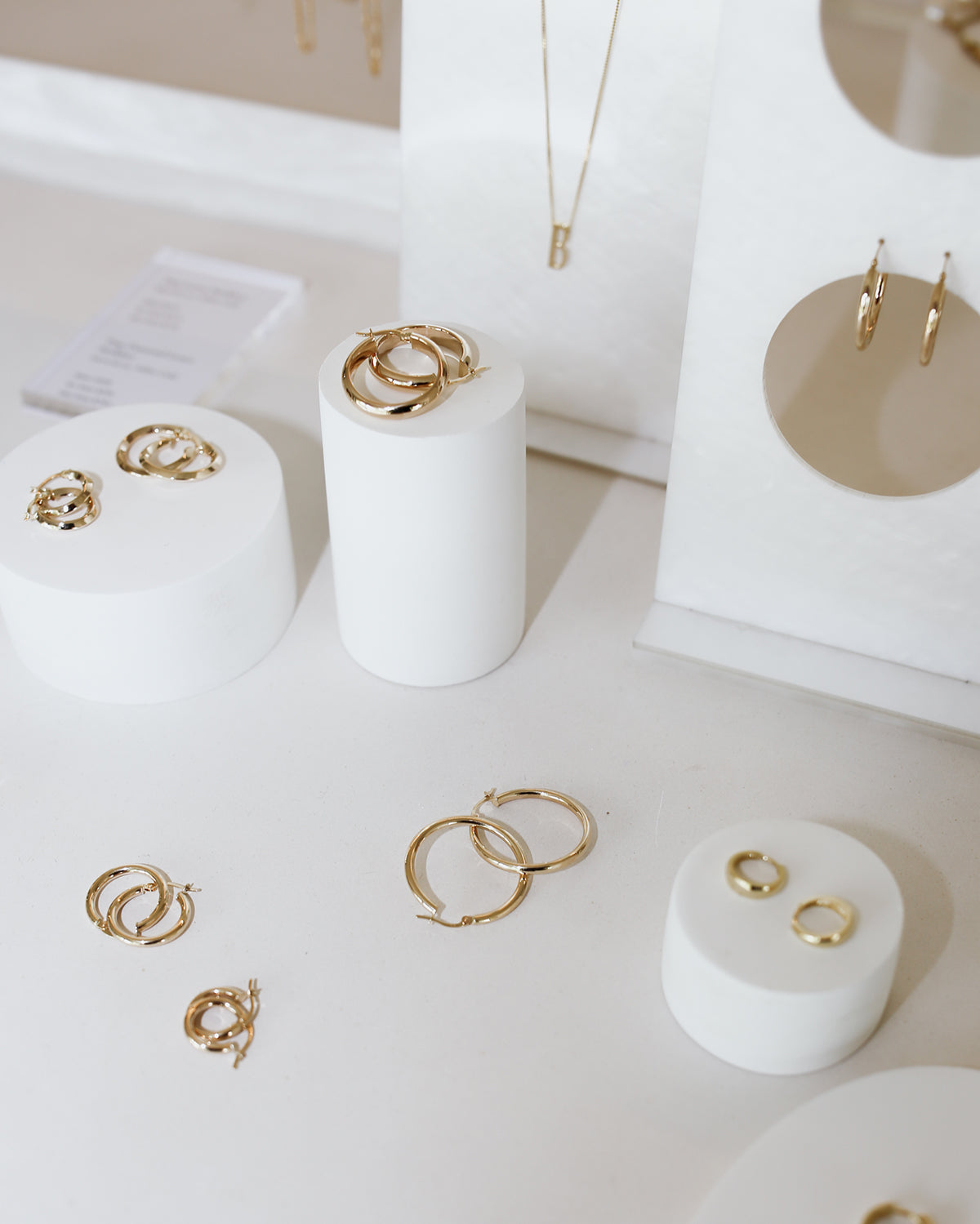 Display of luxury gold hoop earrings on white stands. Various sizes are neatly arranged for a stylish and elegant presentation.