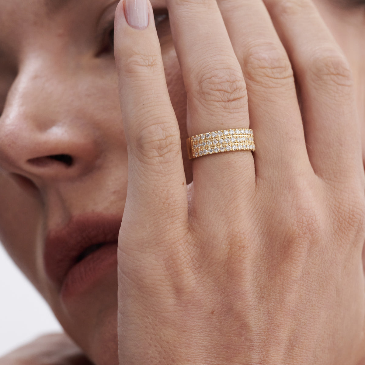 Close-up of a woman's hand with a diamond-encrusted gold ring, showcasing luxury jewellery in an elegant pose.
