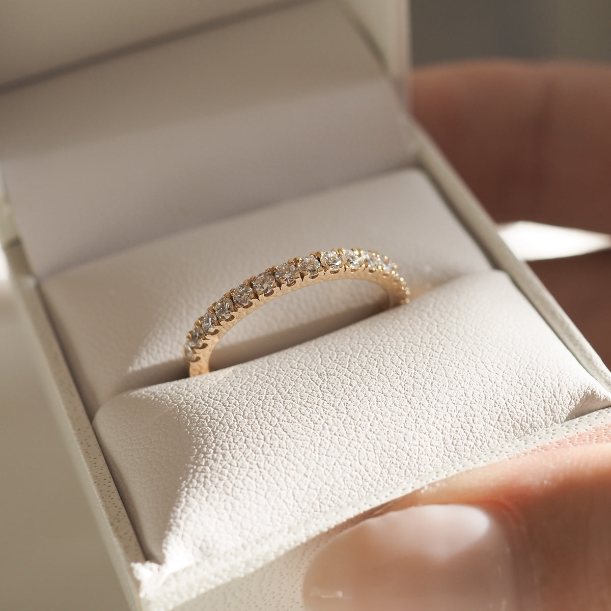 Elegant diamond ring in a white jewellery box, gold band with sparkling diamonds, showcasing luxury and craftsmanship, soft lighting effect.
