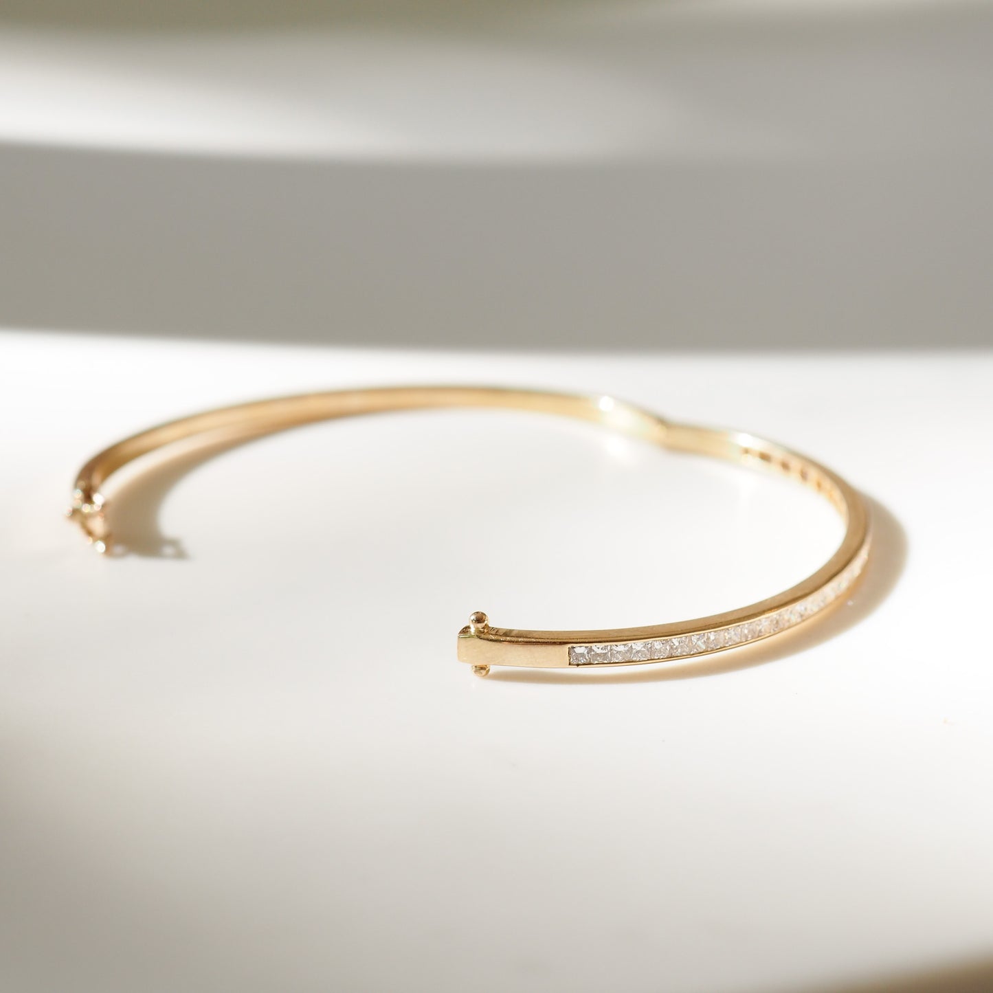 Gold bracelet with small diamonds on a light background