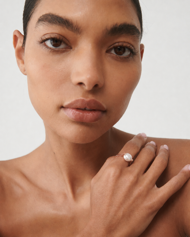 Woman wearing a ring on her finger against a neutral background