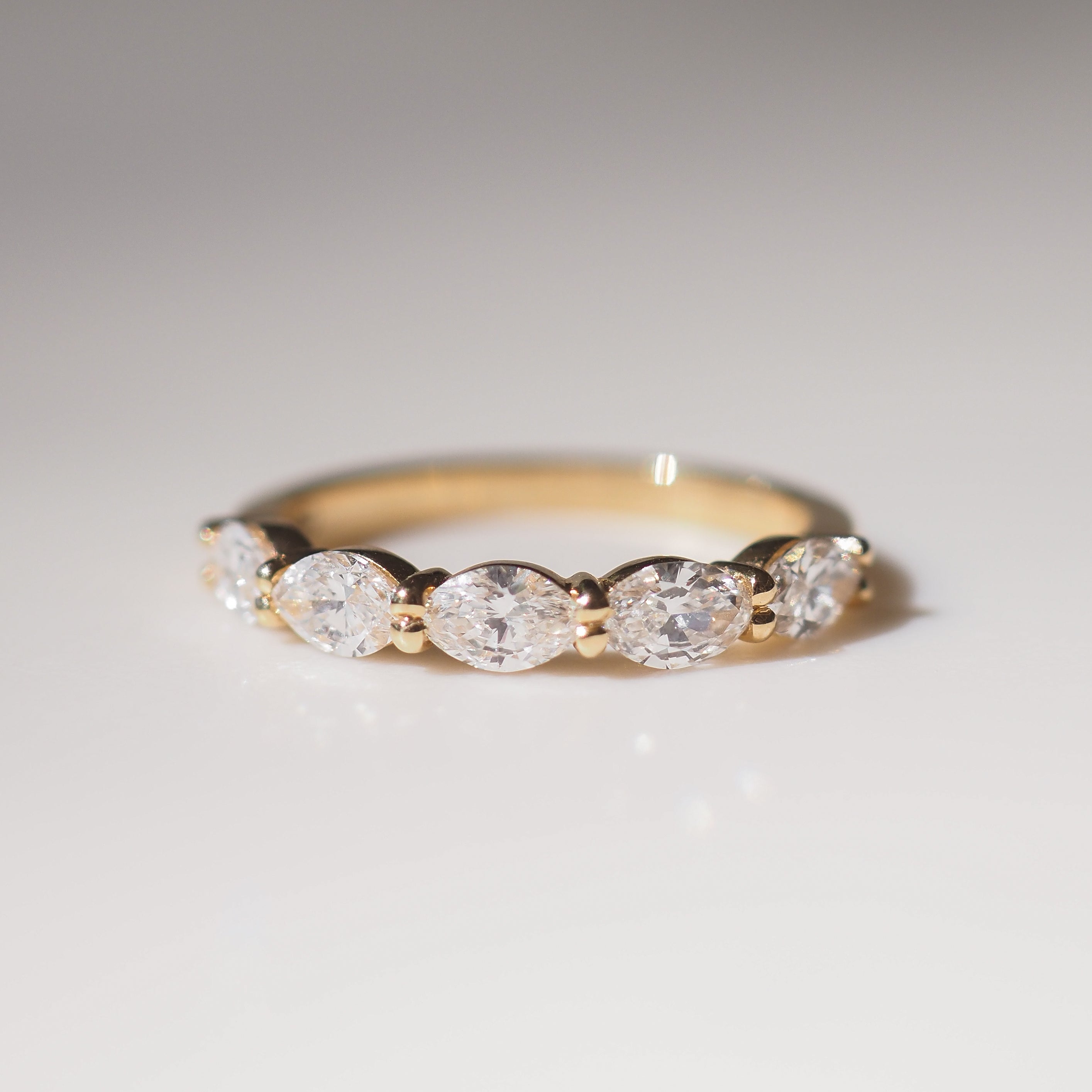 Gold ring with five diamonds on a light gray background