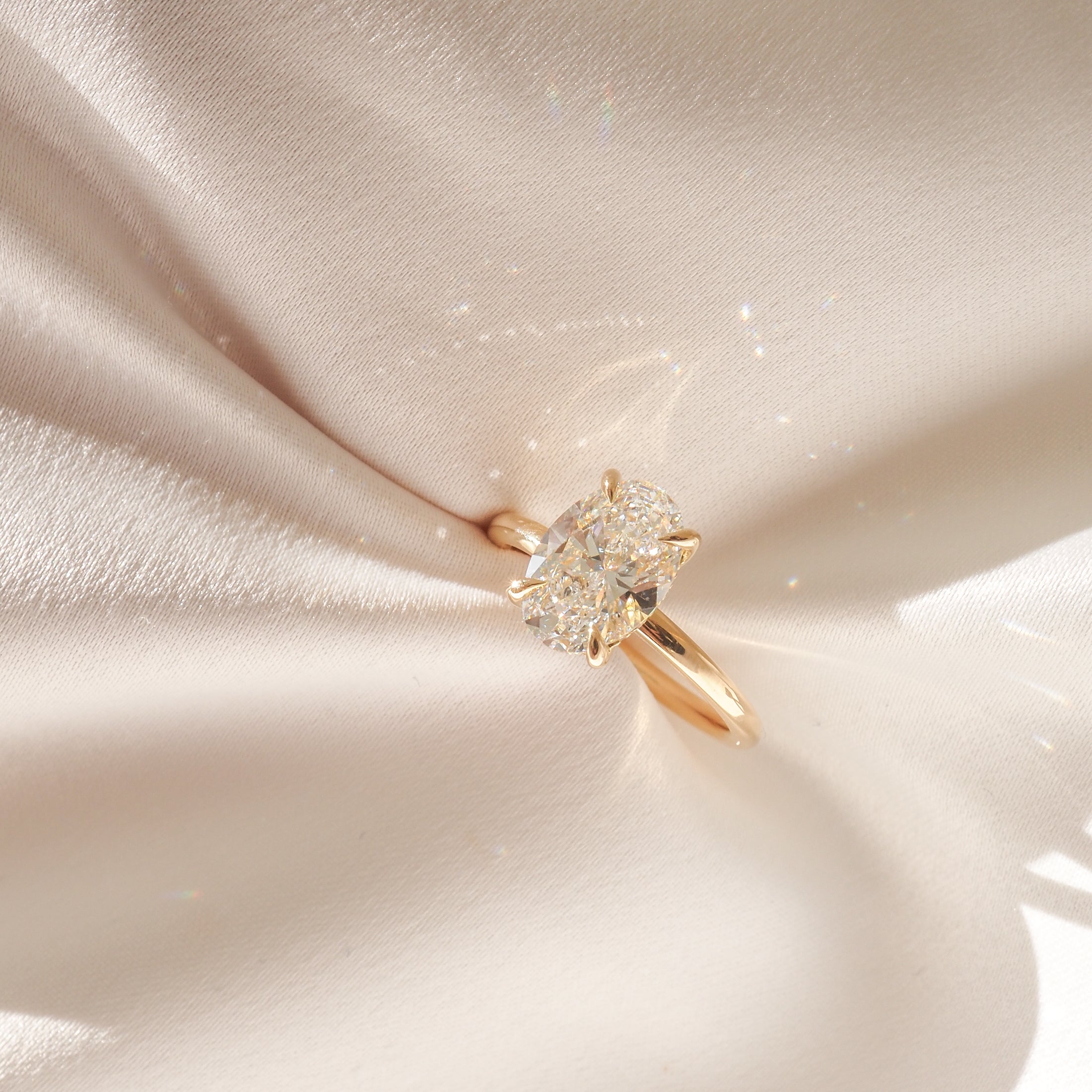 Diamond engagement ring with a gold band on luxurious cream silk fabric, highlighting the gem's sparkle and the elegant setting.