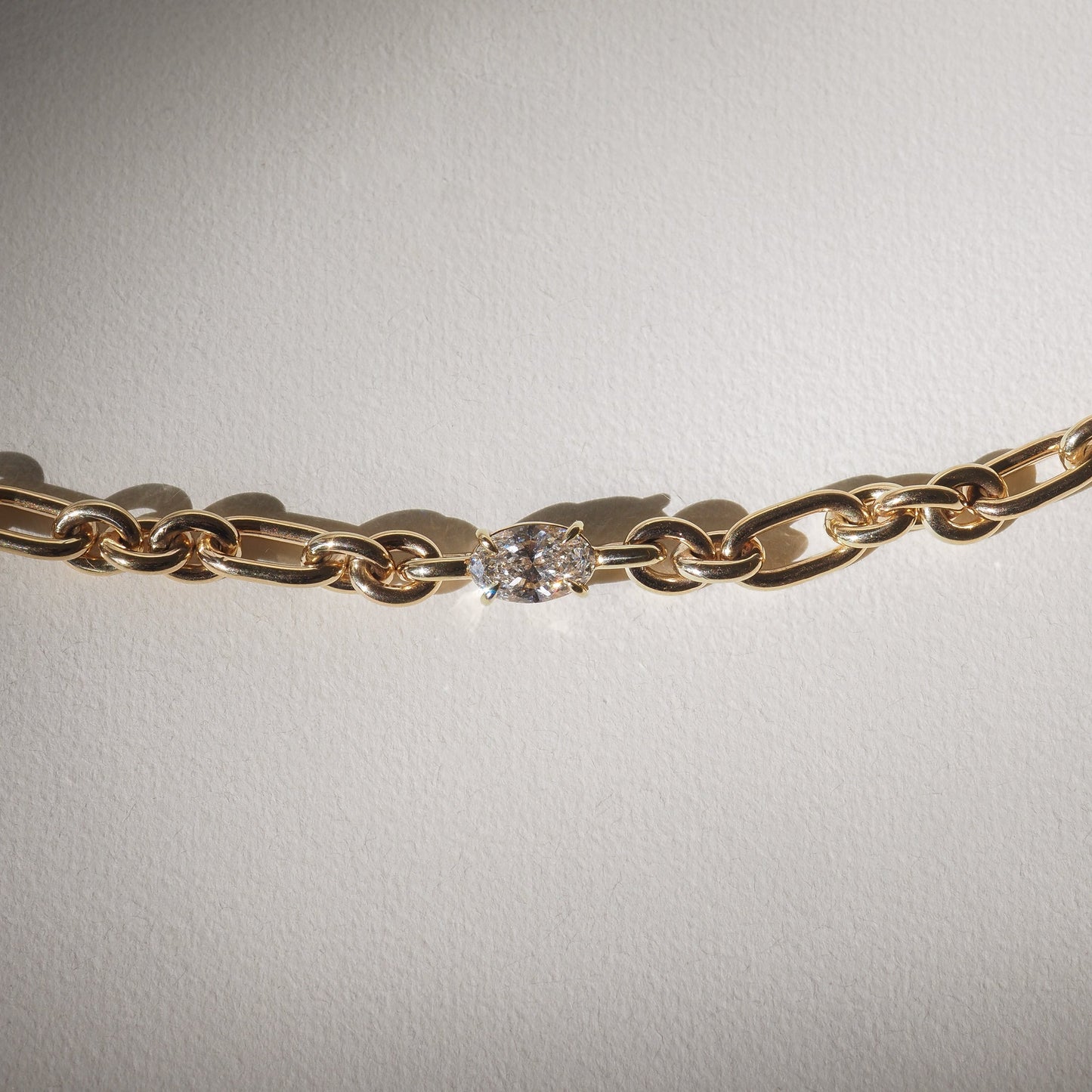 Gold chain necklace featuring an elegant oval diamond centerpiece, set against a light background, showcasing luxury jewellery design.