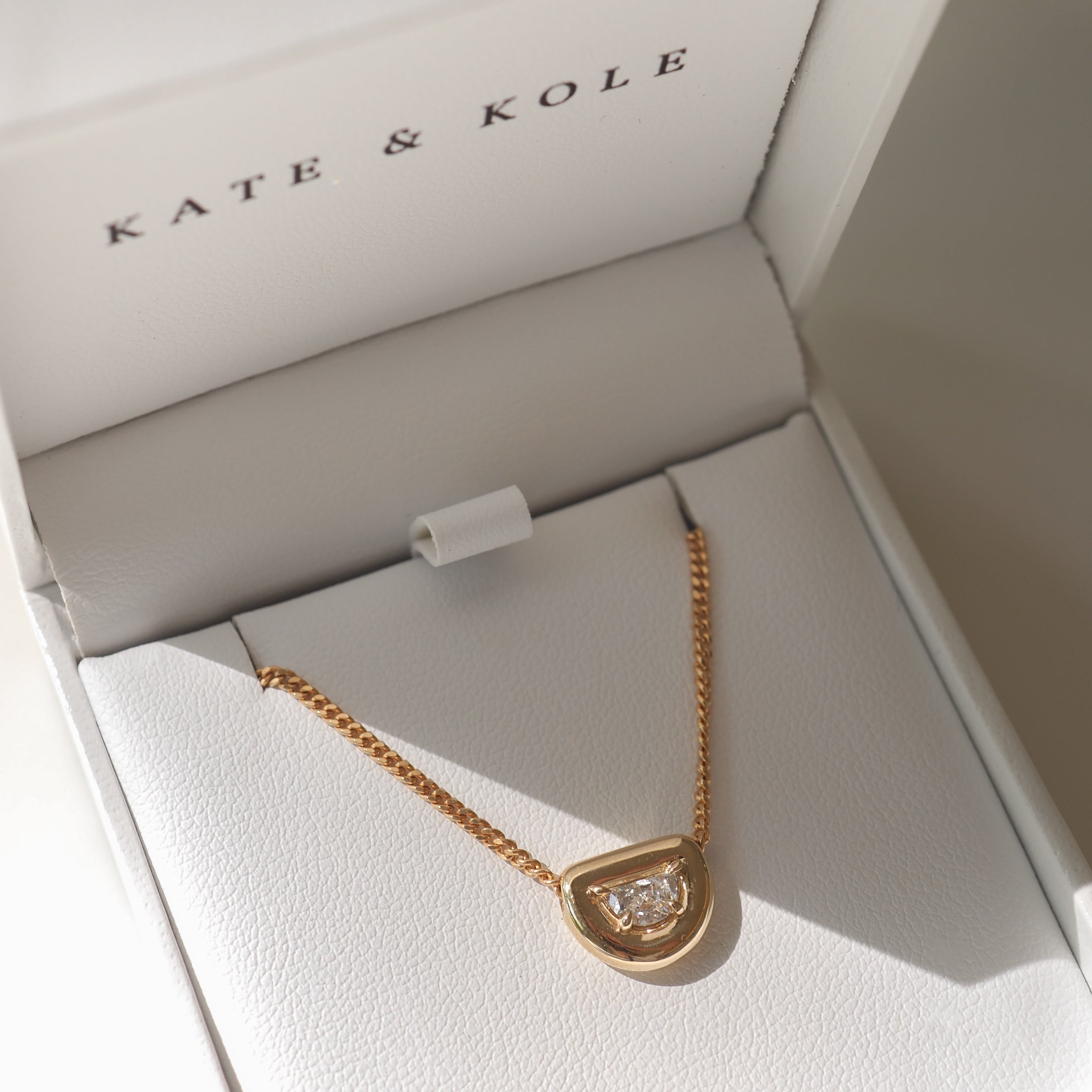 Gold necklace with diamond pendant in a Kate & Kole jewellery box. Elegant and luxurious design, perfect for special occasions.