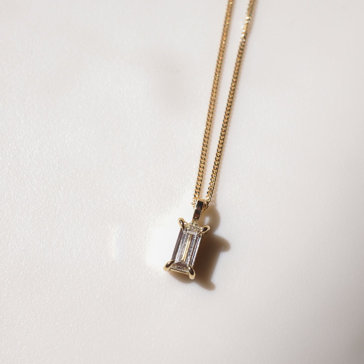 Gold chain necklace featuring a radiant, rectangular gemstone pendant. Subtle elegance in high-end jewellery design.
