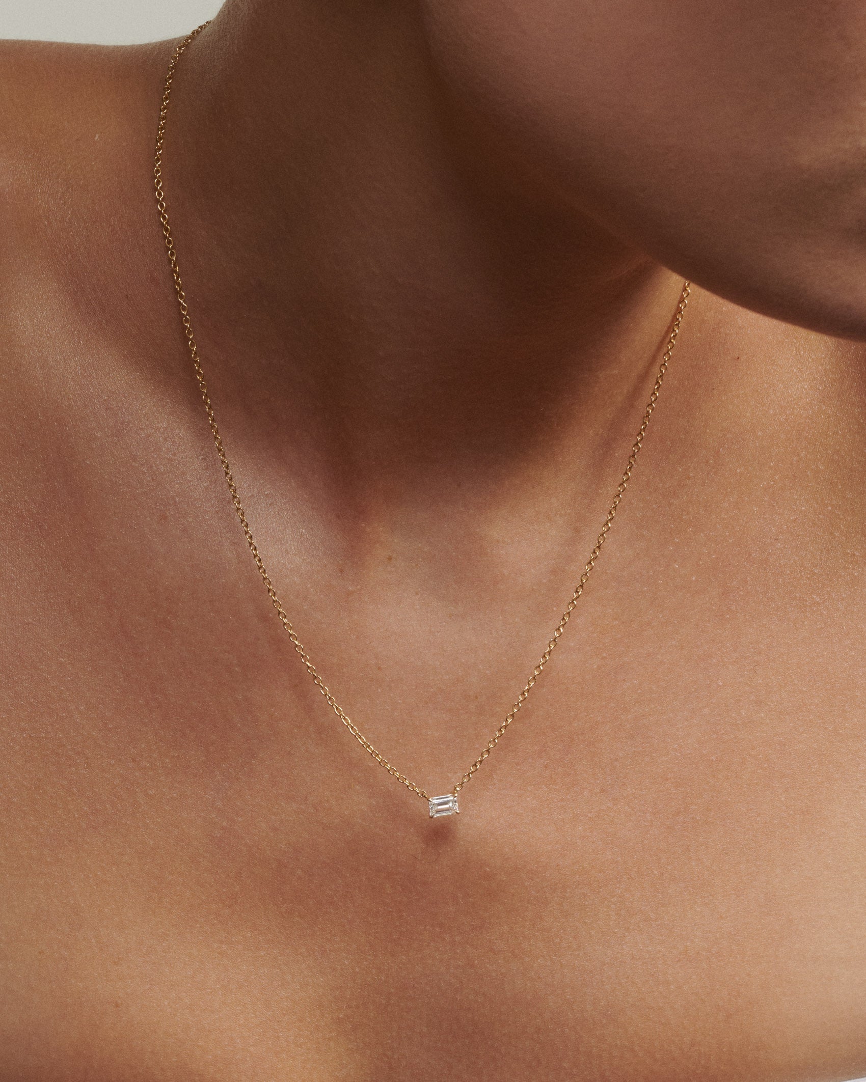 Gold necklace with a small pendant on a person's neck
[text overlay: Andrea wears the 0.5ct Necklace]
