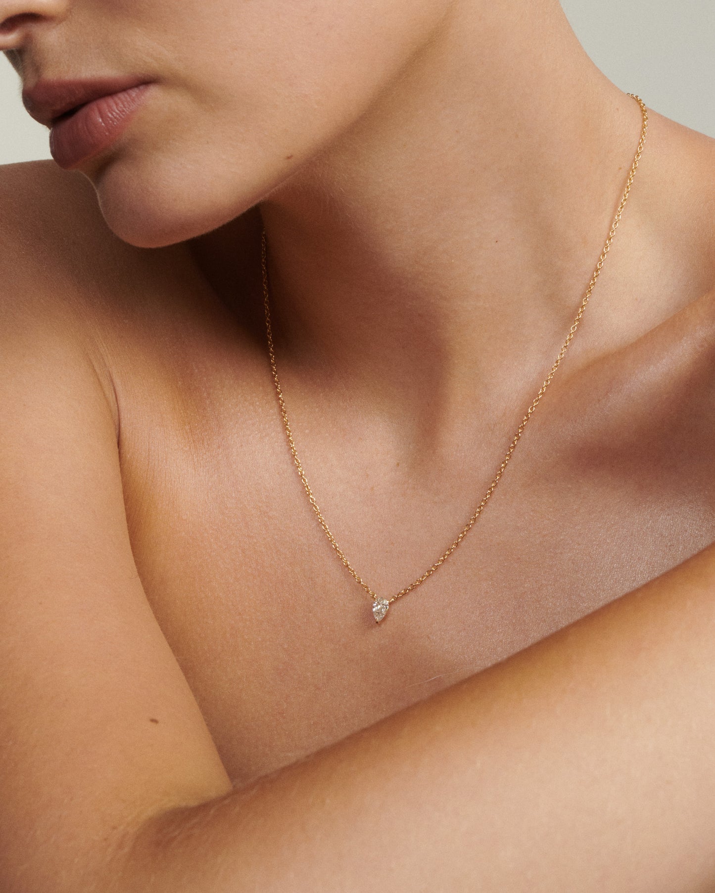 Gold necklace with a small diamond pendant on a person's neck