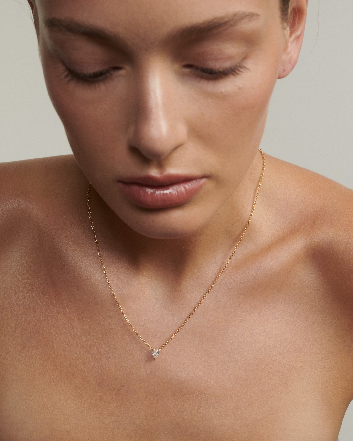 Close-up of a person wearing a delicate necklace with a small diamond pendant.