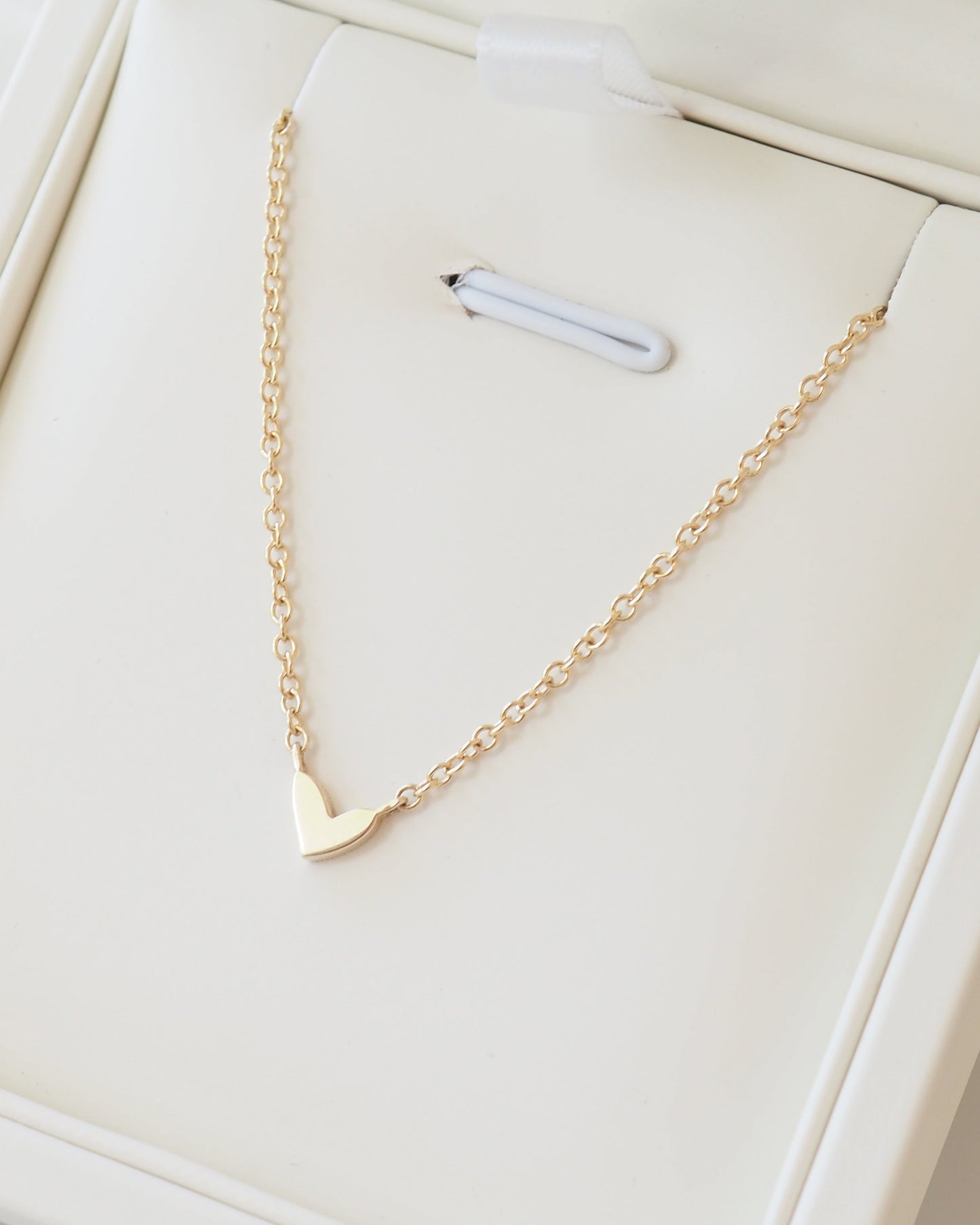 Gold necklace with a triangle pendant on a white surface