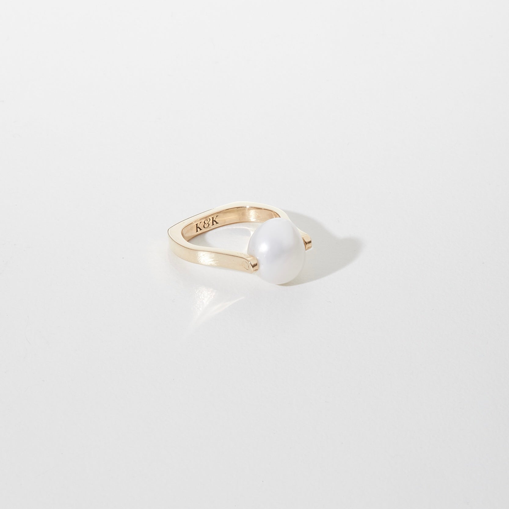 Gold ring with a pearl on a light gray background