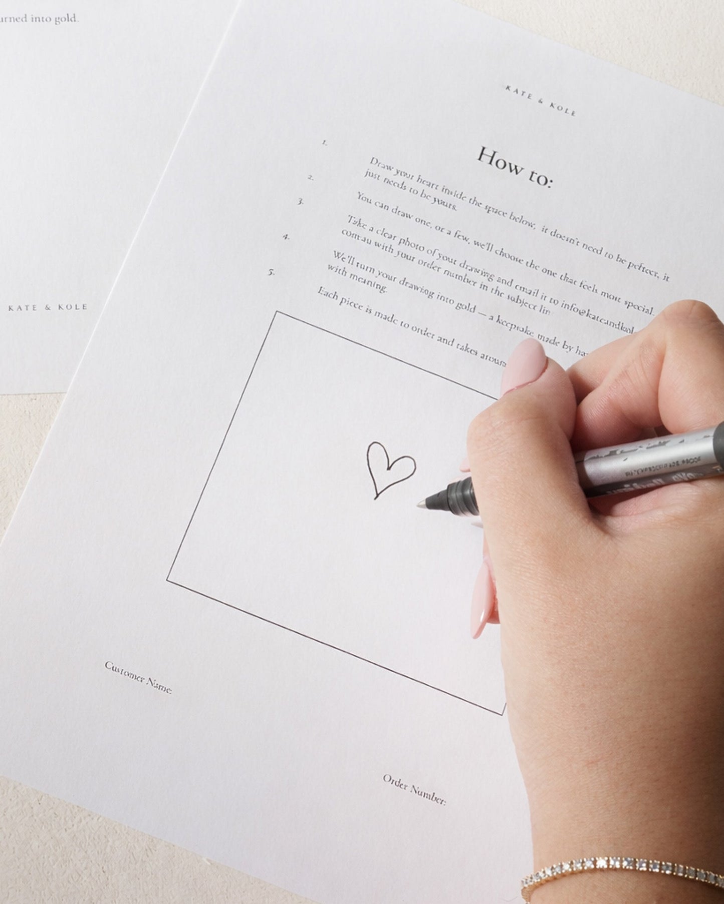 Hand drawing a heart on a piece of paper with a pen.