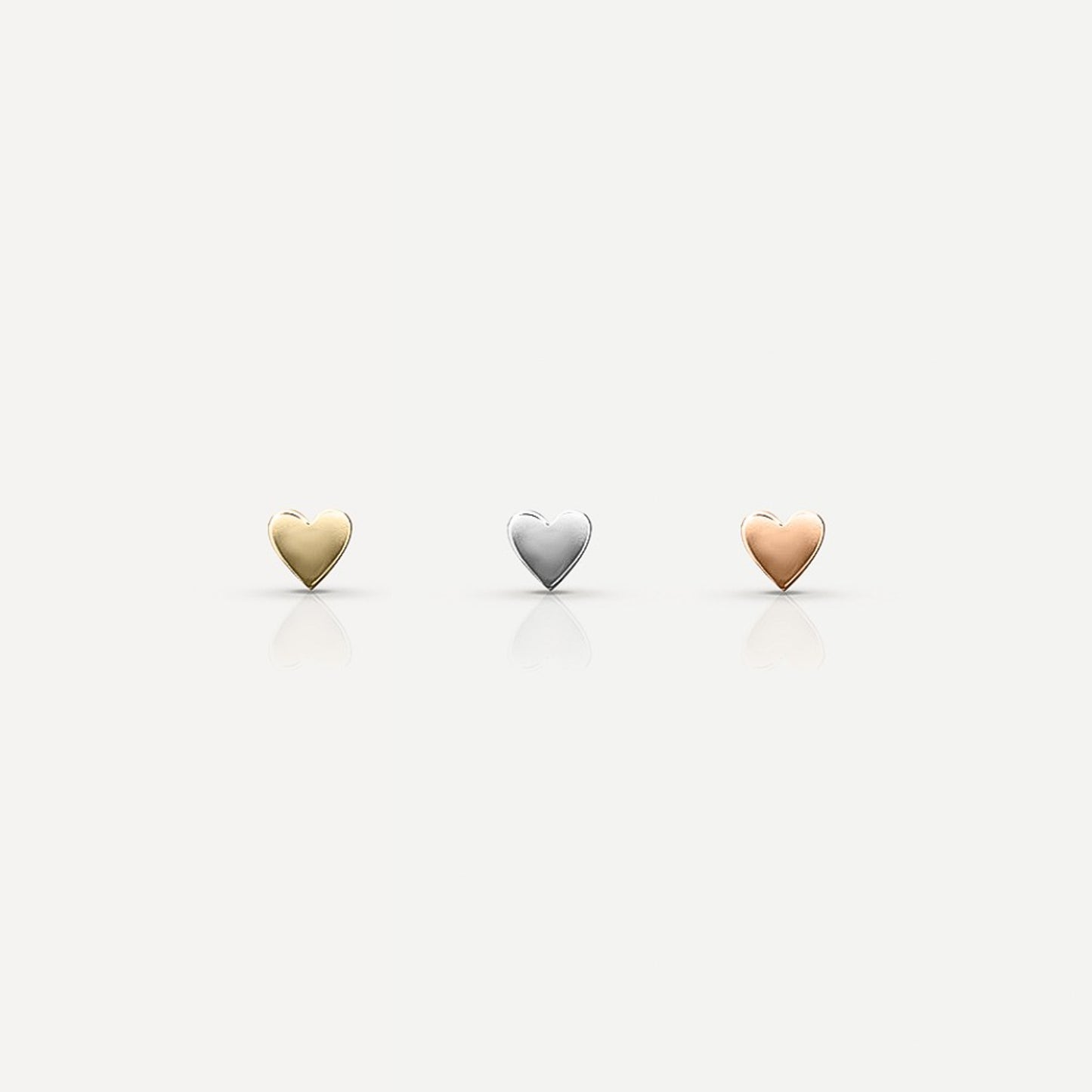 Three heart-shaped jewellery pieces in gold, silver, and rose gold on a plain background, reflecting a luxury aesthetic.[text overlay: Yellow Gold (left), White Gold (middle) and Rose Gold (right)]
