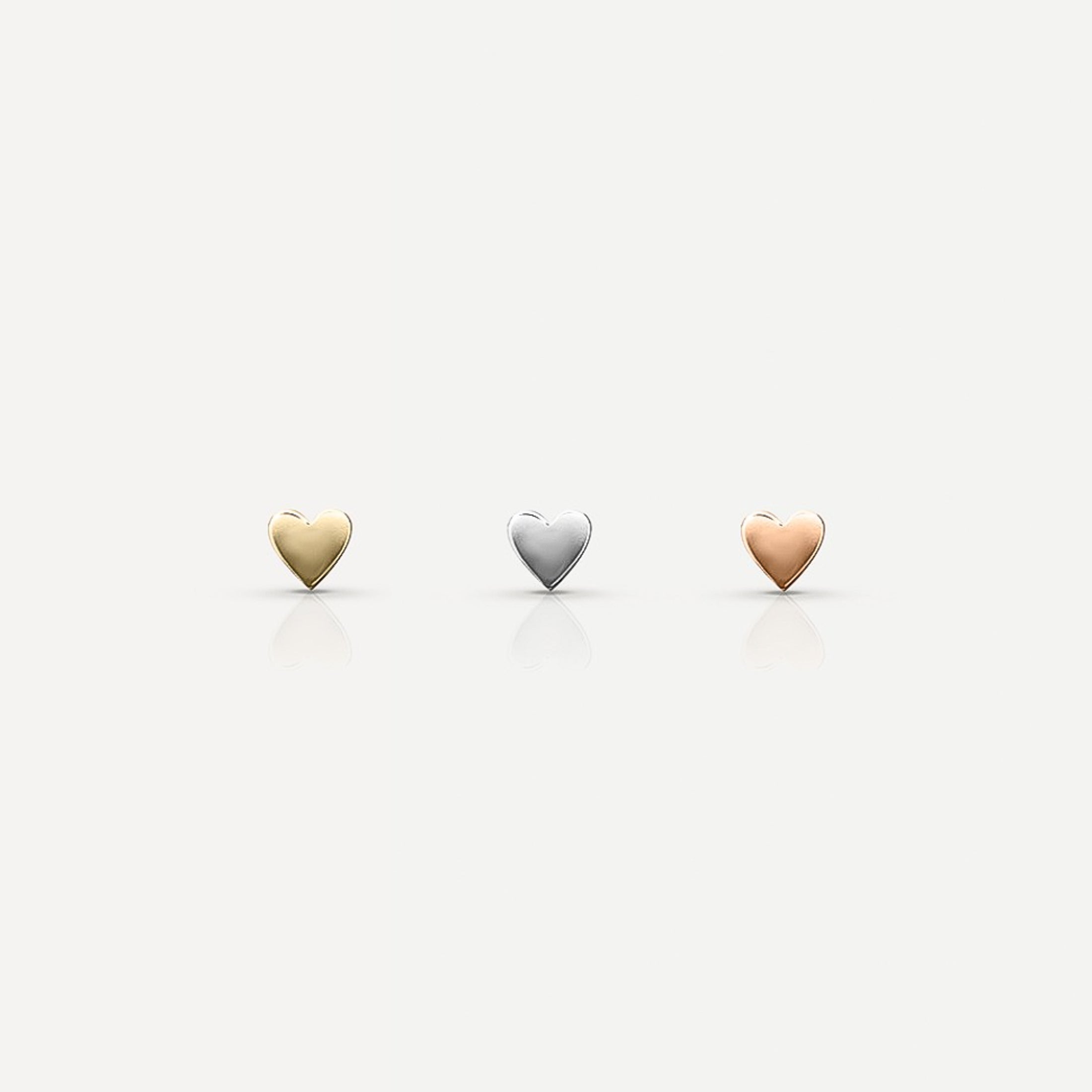 Three heart-shaped jewellery pieces in gold, silver, and rose gold on a plain background, reflecting a luxury aesthetic.[text overlay: Yellow Gold (left), White Gold (middle) and Rose Gold (right)]