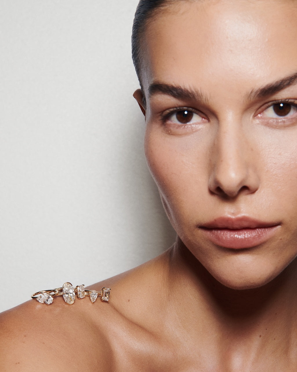 Close-up of a woman's face with a diamond rings on her shoulder