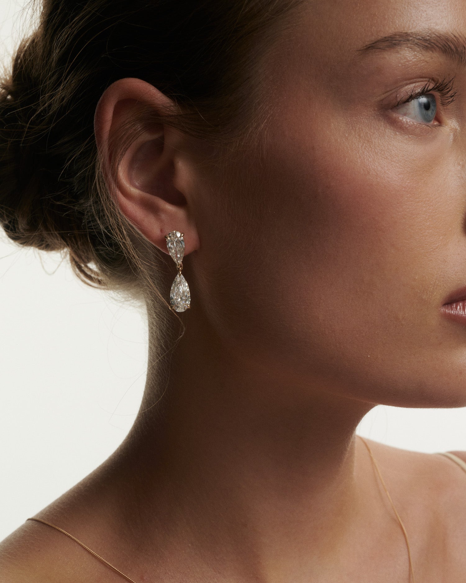 Close-up of a woman wearing a diamond earring with a neutral background