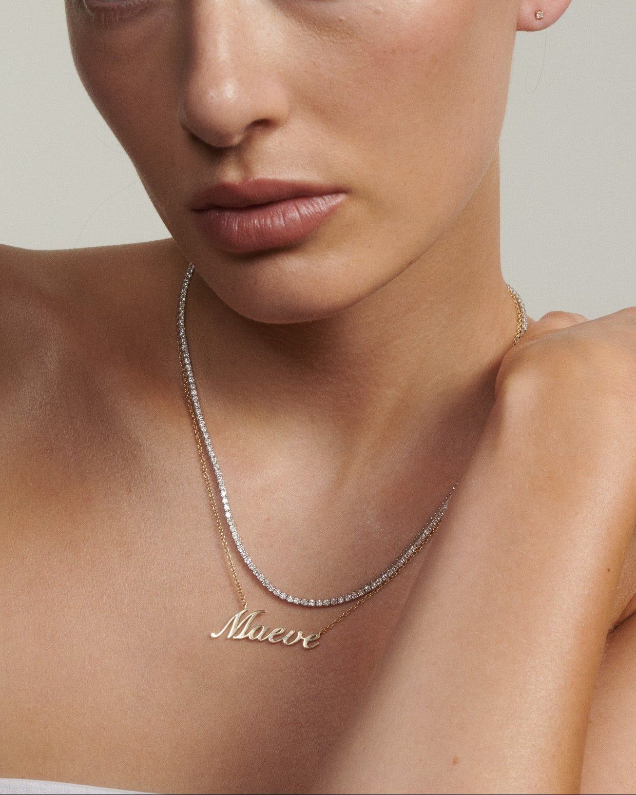 Woman wearing a gold necklace with 'Maeve' on a neutral background