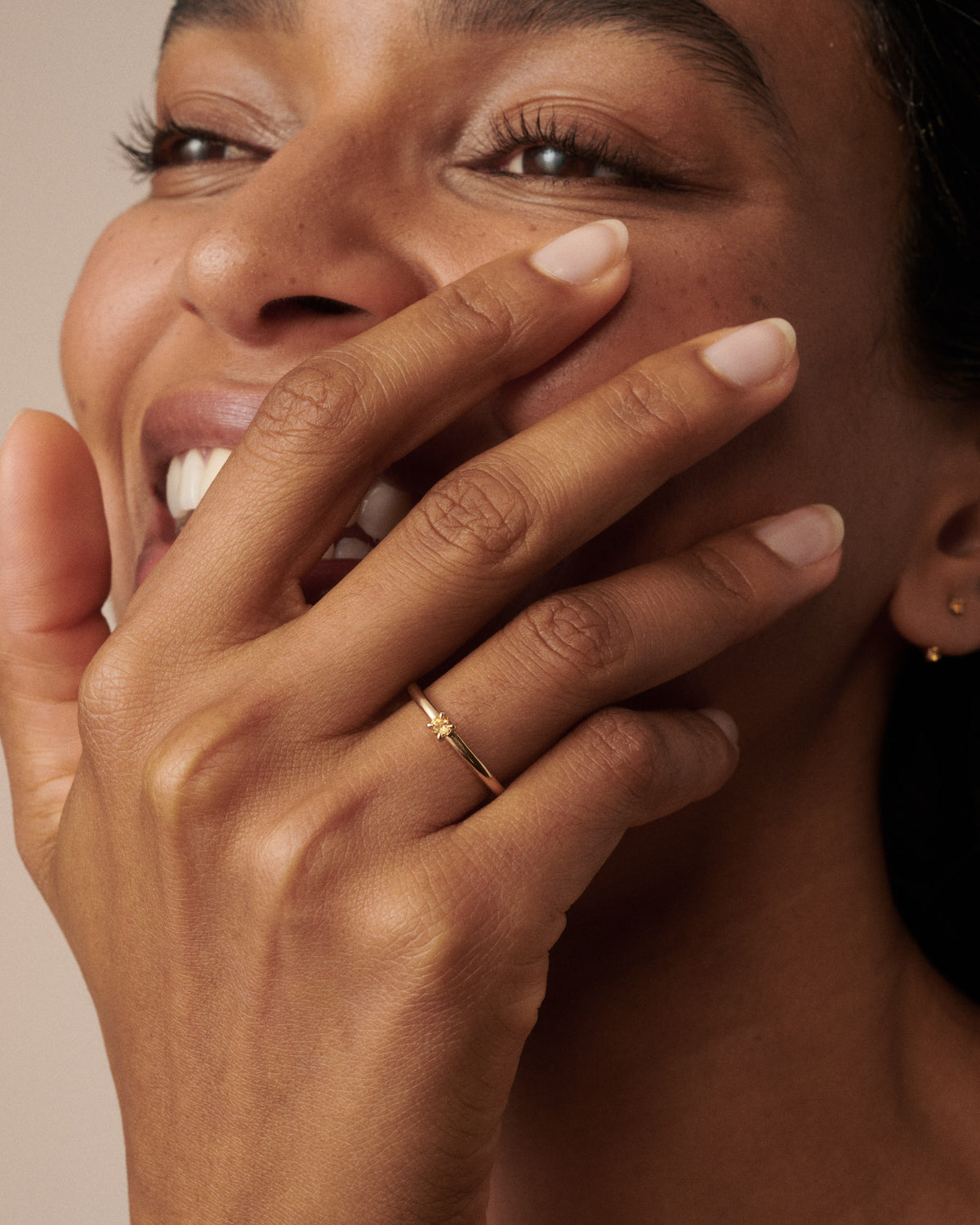 Woman wear a citrine yellow gold birthstone ring while laughing and covering her mouth