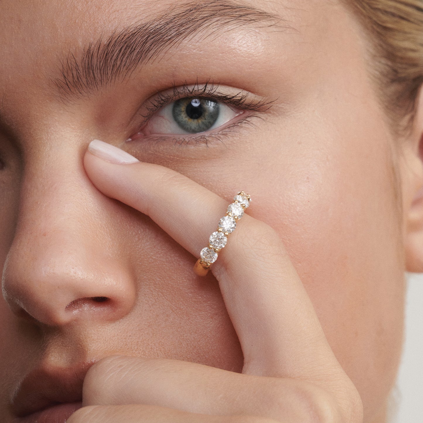 Close-up of a woman's eye with a diamond ring on her finger