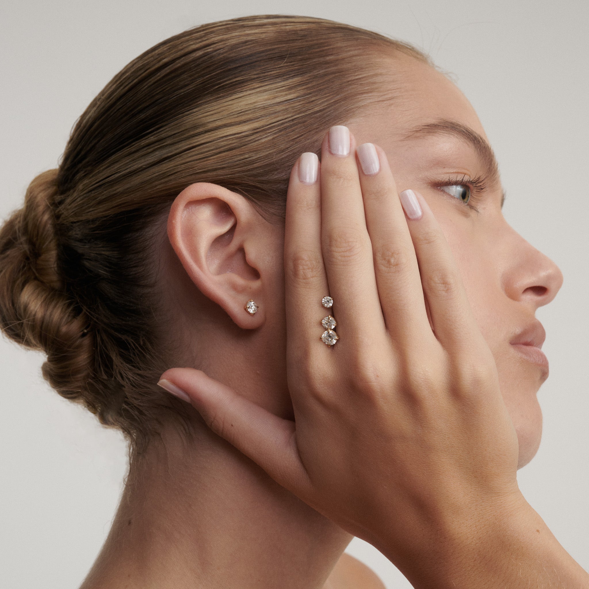 Woman wearing diamond earrings with a neutral background