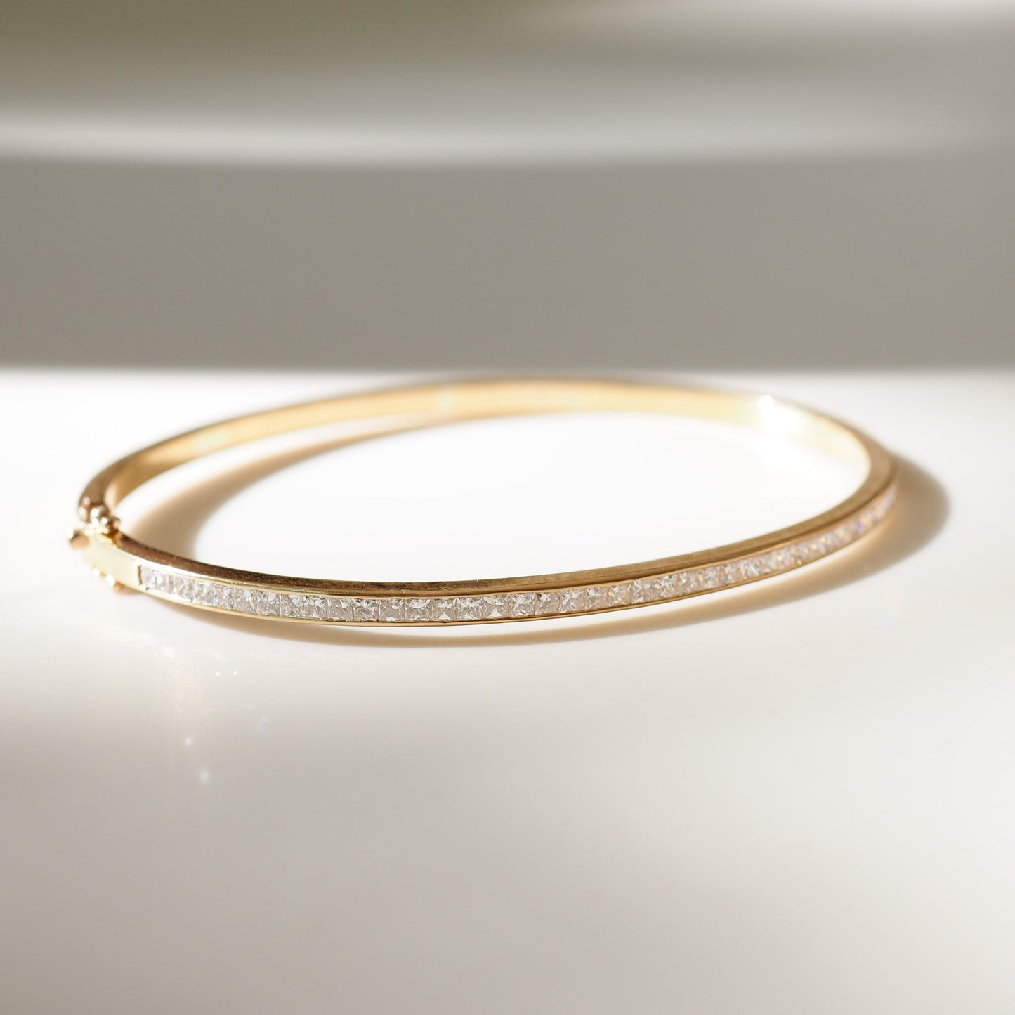 Gold bracelet with small diamonds on a light background