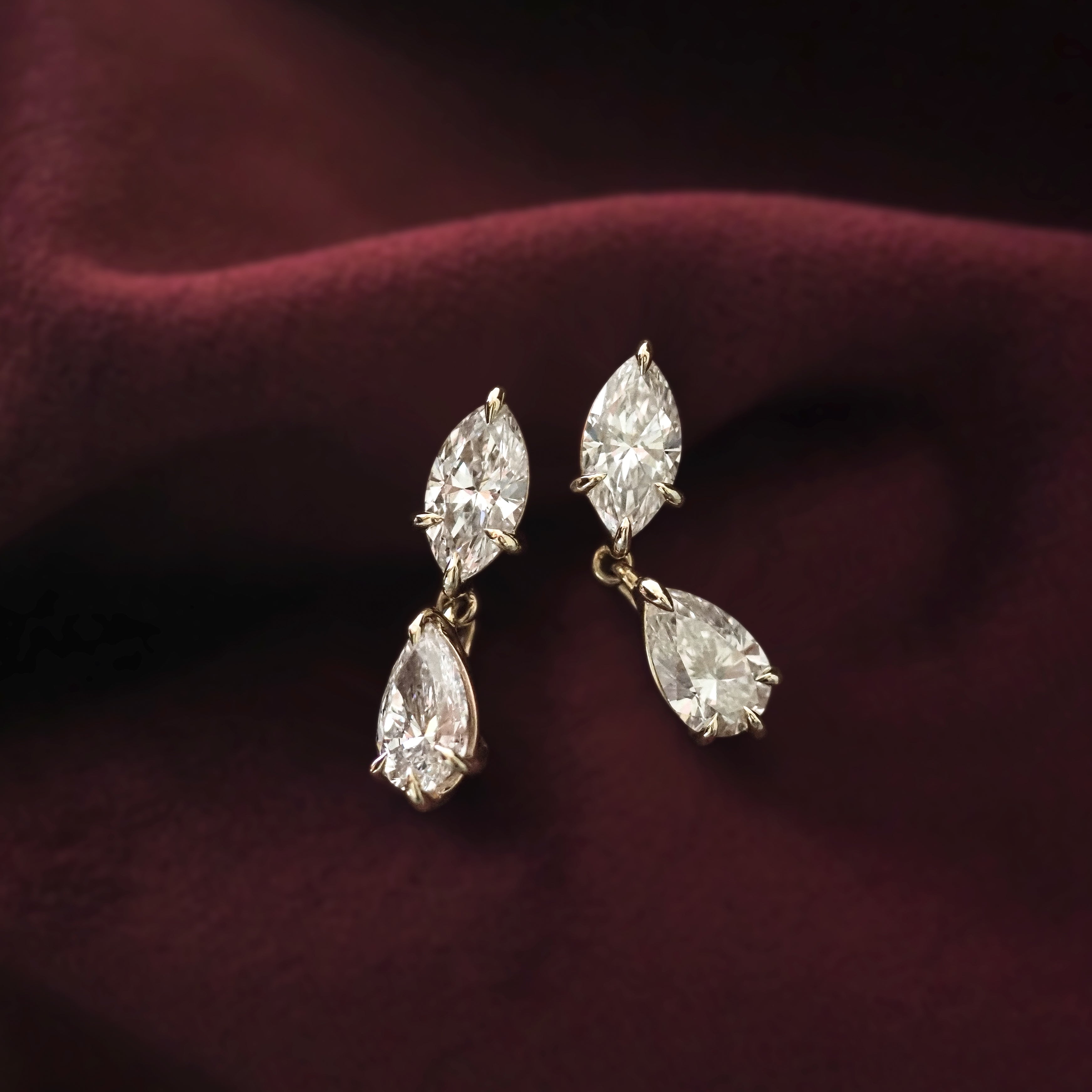 Pair of diamond earrings on a deep red fabric background