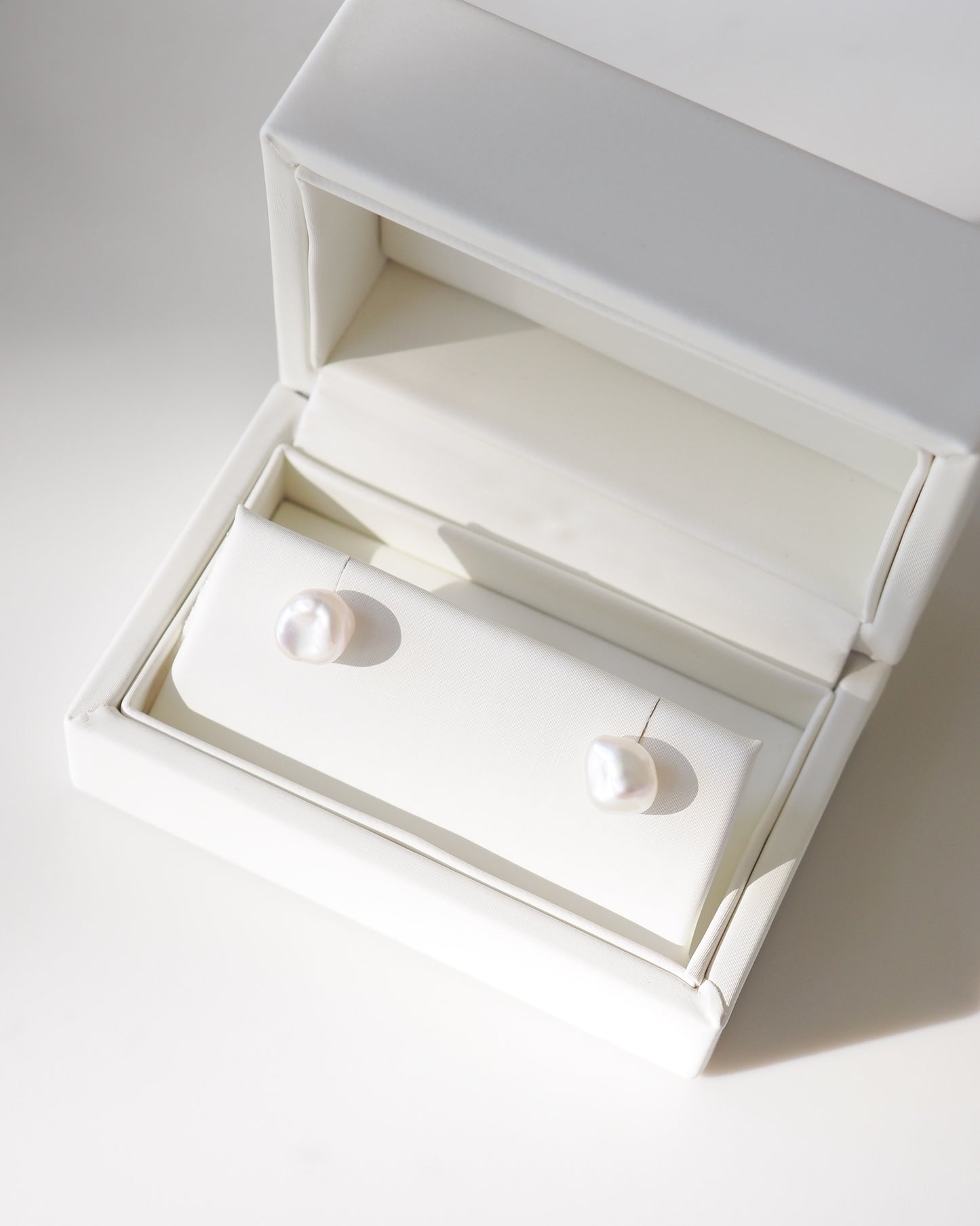 White jewelry box with a ring inside on a light gray background