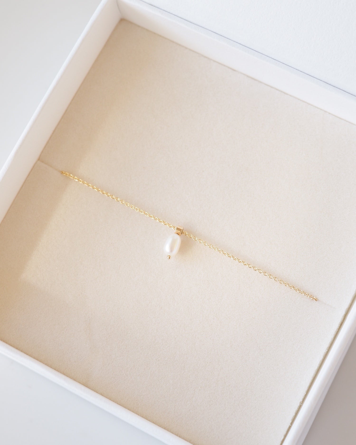 Gold bracelet with a pearl in a white box
