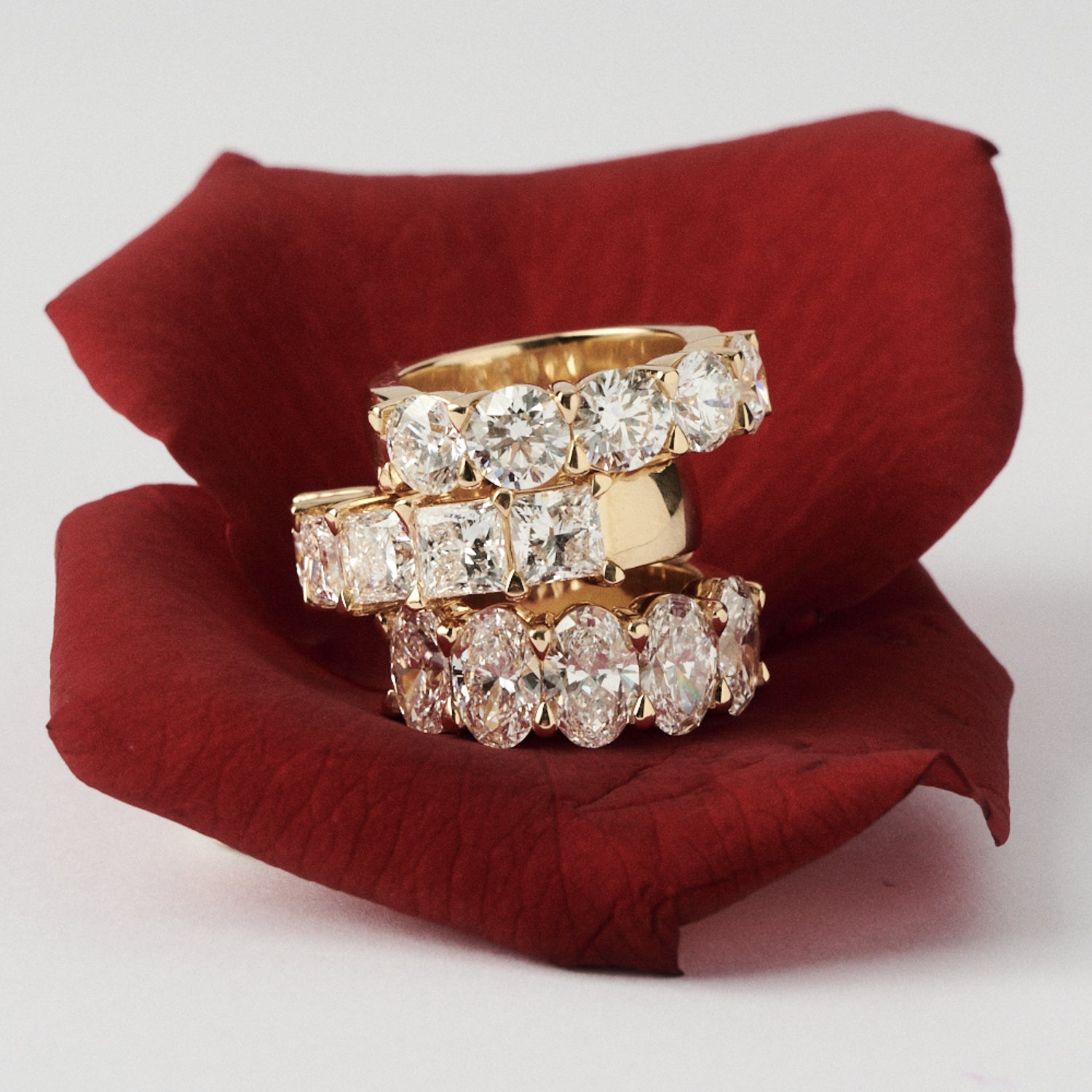 Three gold and diamond rings stacked on a red fabric surface