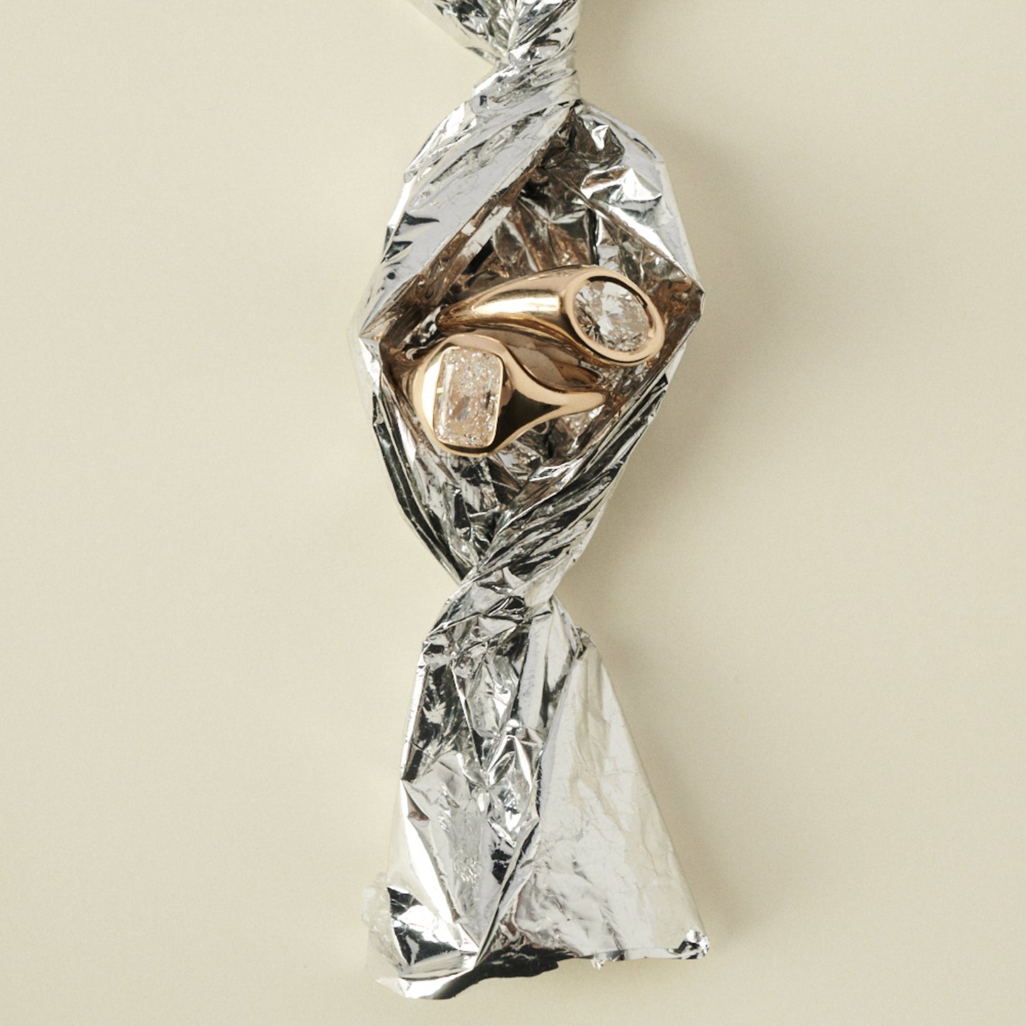 Gold ring with diamonds wrapped in clear plastic on a beige background