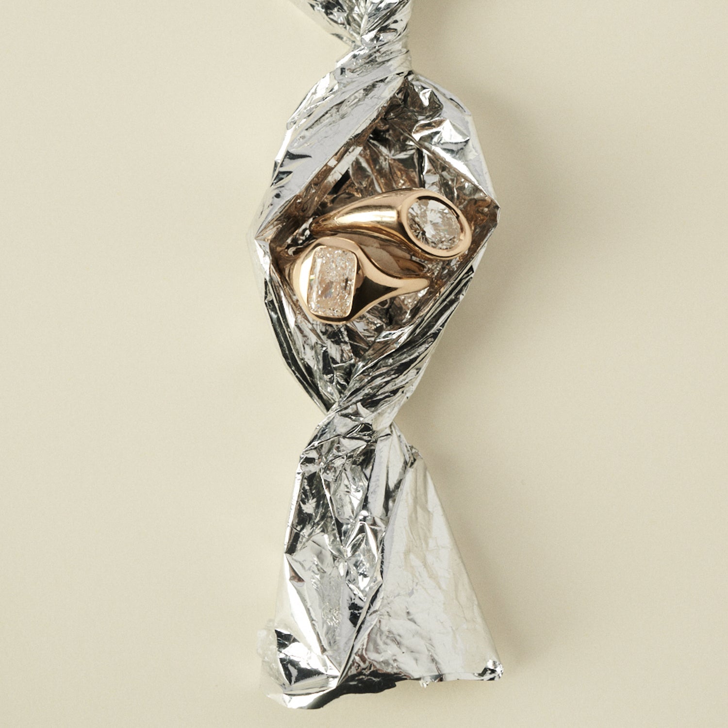 Gold ring with diamonds wrapped in clear plastic on a beige background