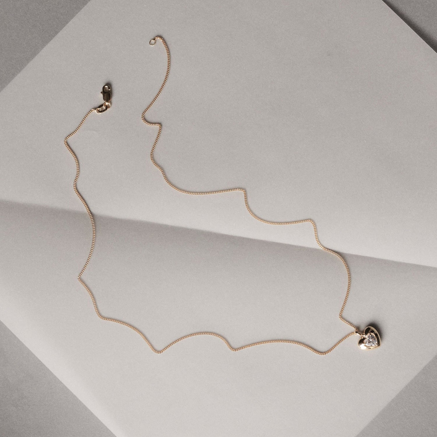 Gold necklace on a light gray surface