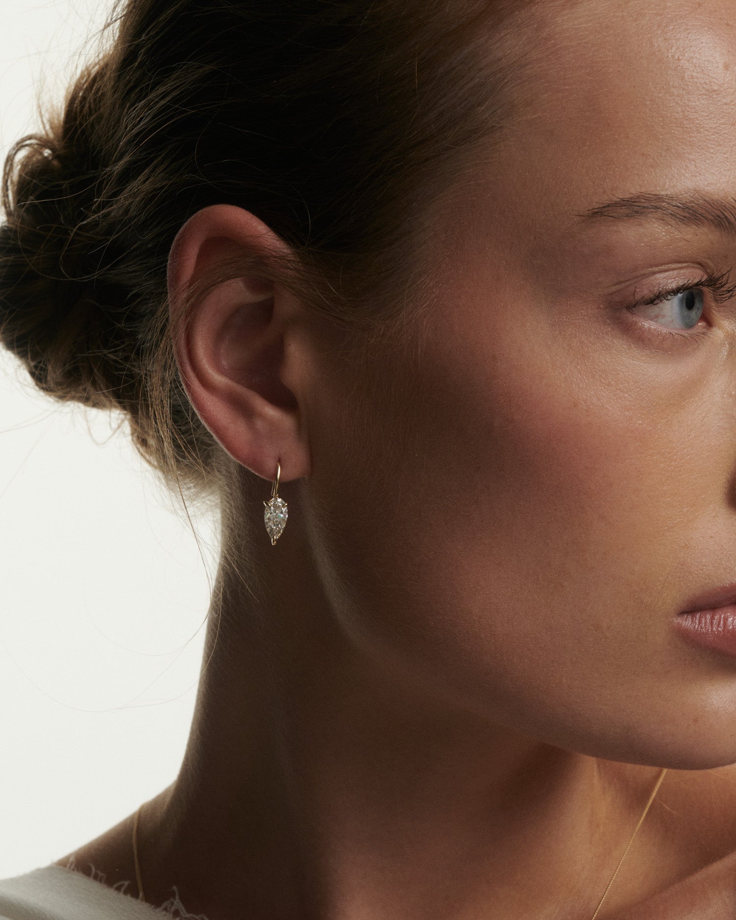 Close-up of a woman wearing a diamond earring with a neutral background