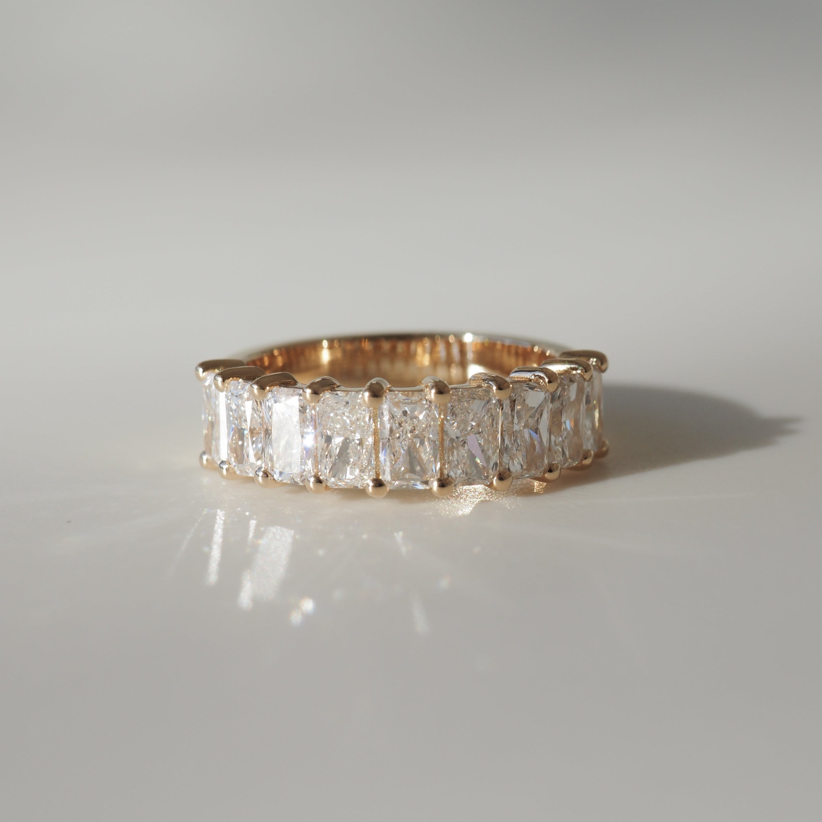 Gold ring set with rectangular diamonds, elegantly staged on a light surface, showcasing luxury jewellery craftsmanship.