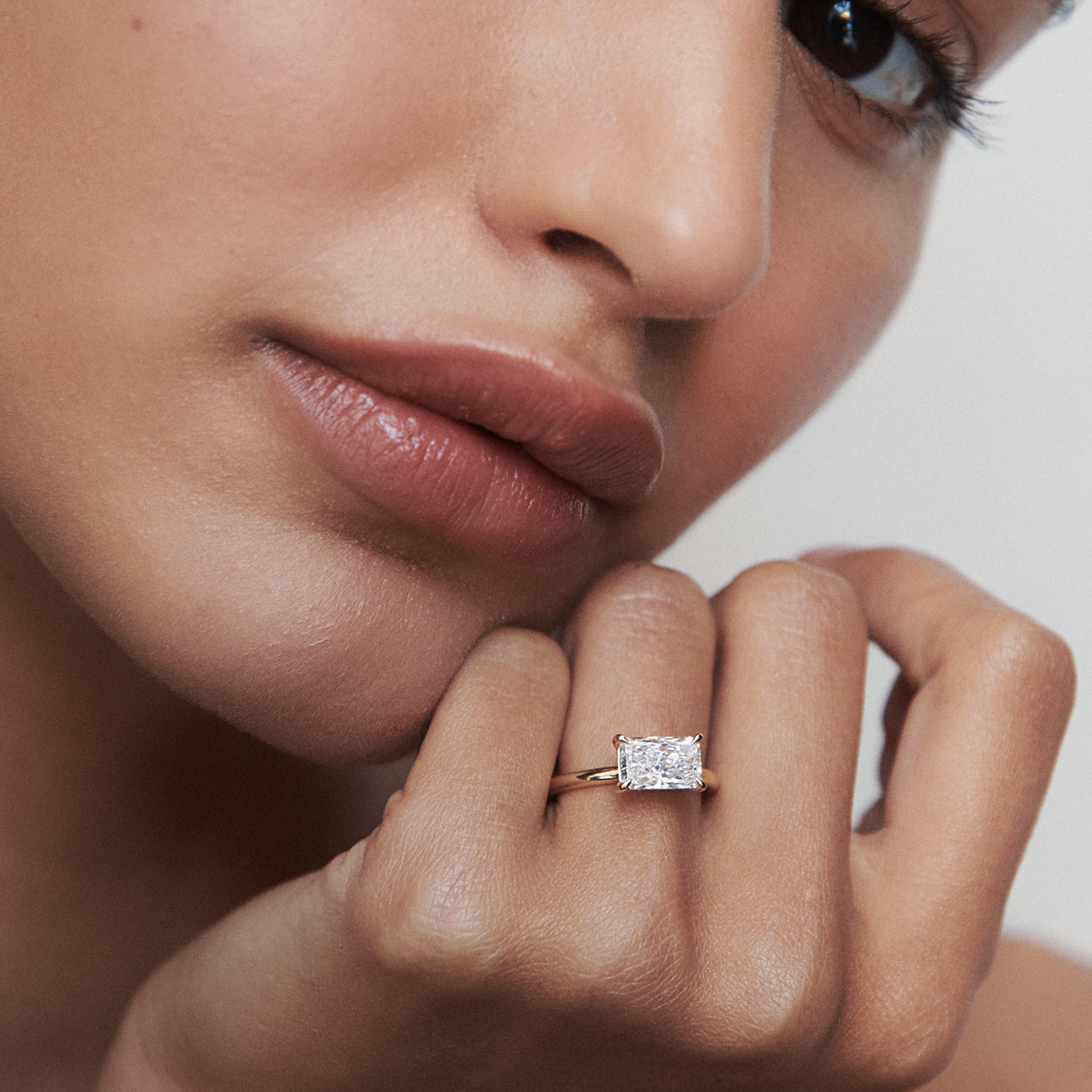 Close-up of a woman showcasing a radiant-cut diamond ring on her finger, highlighting luxury and elegance in jewellery design.