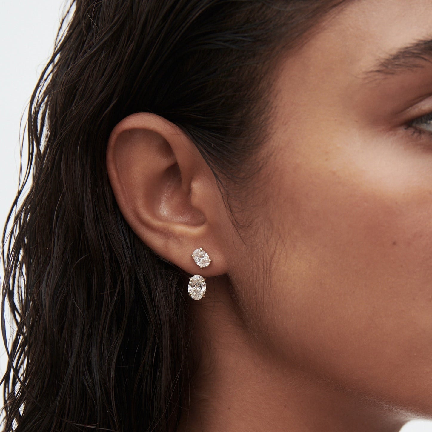 Woman with wet hair wearing two luxury diamond earrings. Her profile view highlights elegant jewellery, emphasising luxury style and sophistication.