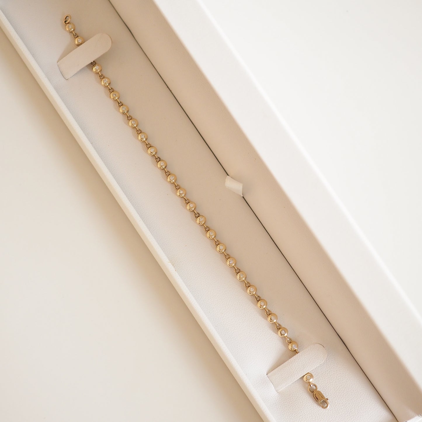 Gold bracelet with small links in an elegant cream jewellery box.