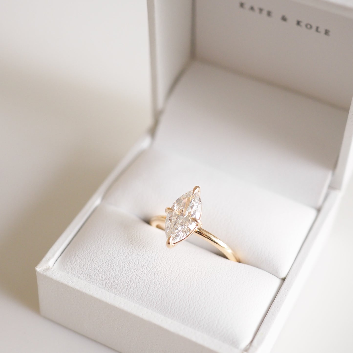 Marquise diamond ring in gold setting displayed in an open jewellery box, labelled "Kate & Kole".